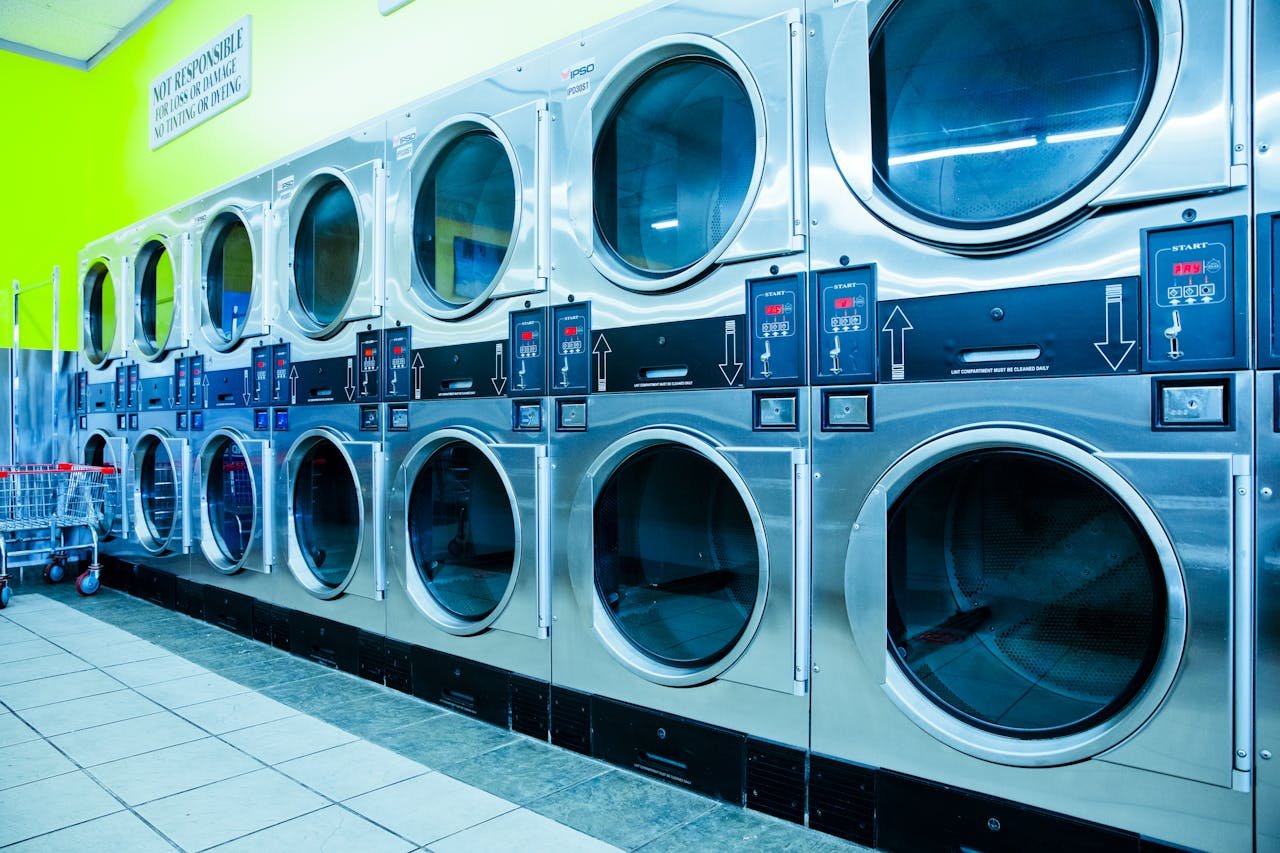 Bright laundromat with rows of industrial washing machines and vibrant green walls.
